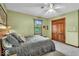 Bedroom features green walls, carpeted floor, ceiling fan, a large window, and closet with wood door at 2011 Pin Oak Ct, Indianapolis, IN 46260