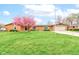 Charming brick home with a well-manicured lawn and a beautiful pink flowering tree in the front yard at 4013 Colonial Dr, Anderson, IN 46012