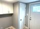 Bright laundry room with a storage cabinets, gray walls, and access to an exterior door at 410 S 25Th Ave, Beech Grove, IN 46107
