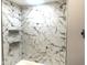 Modern bathroom shower featuring sleek marble-patterned tile and convenient built-in shelving at 410 S 25Th Ave, Beech Grove, IN 46107