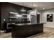 Modern basement kitchen with stainless steel refrigerator, dark cabinets, and stone countertops at 4292 Alderborough Way, Zionsville, IN 46077