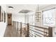 Upstairs hallway featuring hardwood floors, modern chandelier lighting, and large windows with neighborhood views at 4292 Alderborough Way, Zionsville, IN 46077
