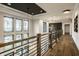 Bright hallway with wood floors, rustic railing, modern lighting, and large windows, offering an inviting and airy atmosphere at 4292 Alderborough Way, Zionsville, IN 46077