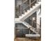 Modern staircase featuring white risers, wooden handrails, and black metal balusters, enhanced by natural light and neutral wall colors at 4292 Alderborough Way, Zionsville, IN 46077
