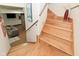 Wooden staircase connecting floors with a view into a cozy basement living space and adjacent decorative stone wall at 5528 State Road 144, Greenwood, IN 46143