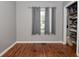 Bedroom with hardwood floors, gray walls, and window with curtains, complemented by a tidy closet at 5693 W Walnut St, Greenwood, IN 46142