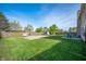 Spacious backyard with a grassy lawn, trees, basketball hoop, and seating area at 5886 N Peppereel Way, McCordsville, IN 46055