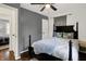 Bright bedroom displays wood floors, a decorative gray accent wall, black bed frame with patterned pillows and ceiling fan at 6106 Evanston Ave, Indianapolis, IN 46220