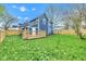 A view of a spacious backyard, featuring a blue house, wooden deck, fence, and green grass at 614 Park Ave, Anderson, IN 46012