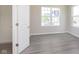 Bright bedroom featuring gray wood floors, a large window, and a white door with silver hardware at 7215 Barrett Dr, Brownsburg, IN 46112