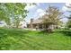 Well-manicured backyard with patio, fireplace, lush green grass, and mature trees at 7340 Stones River Dr, Indianapolis, IN 46259