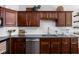 A kitchen features dark wood cabinetry, a stainless dishwasher, a double basin sink, and subway tile backsplash at 7340 Stones River Dr, Indianapolis, IN 46259