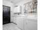Bright laundry room with white appliances, cabinetry, and modern black door at 7340 Stones River Dr, Indianapolis, IN 46259