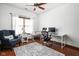 This home office features a ceiling fan, hardwood floors, a desk, and a comfortable chair near a window at 7340 Stones River Dr, Indianapolis, IN 46259