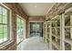 Bright sunroom with brick walls, sliding glass door, shelving, and tile floors at 7340 Stones River Dr, Indianapolis, IN 46259