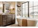 The bathroom boasts a soaking tub, large windows, dark cabinets, and modern fixtures for a sleek and relaxing design at 8082 Abington Way, Zionsville, IN 46077