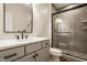 Modern bathroom with a tiled shower, black hardware, gray vanity, and a round mirror at 8092 Abington Way, Zionsville, IN 46077