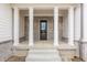Inviting front porch with substantial brick pillars and a modern solid wood front door at 8092 Abington Way, Zionsville, IN 46077