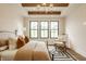 Bright main bedroom with wooden beam ceiling, chandelier, large windows, and stylish decor at 8092 Abington Way, Zionsville, IN 46077