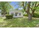 Exterior shot of a quaint single-story home featuring lush greenery, mature trees, and a well-manicured lawn at 819 E Mills Ave, Indianapolis, IN 46227
