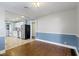 A traditional living room is shown featuring blue wainscoting, hardwood floors and connection to an adjacent kitchen at 819 E Mills Ave, Indianapolis, IN 46227