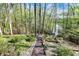 View of a wooded backyard with a wooden staircase descending toward a lake and boat dock at 8191 S Bayview Ct, Trafalgar, IN 46181