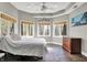 Bright bedroom features a tray ceiling, fan, three windows with a treeline view, and stone tile floors at 8191 S Bayview Ct, Trafalgar, IN 46181