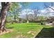 Large backyard with green lawn, mature trees, a wooden fence, and a glimpse of the house's exterior at 8332 Tanager Ln, Indianapolis, IN 46256