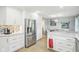 Spacious kitchen showcasing stainless steel refrigerator, white cabinetry, and an island with seating and open floorplan at 8332 Tanager Ln, Indianapolis, IN 46256