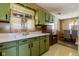 Vintage kitchen with olive-green cabinets that lead into the dining room space with a retro hanging lamp at 9570 S 300 W, Columbus, IN 47201