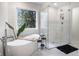 Luxurious bathroom with standalone tub, glass shower, and leafy plant in a bright space at 12011 Glen Cove Dr, Indianapolis, IN 46236