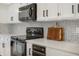 Well-lit kitchen features white cabinets, sleek black hardware, black appliances and marble countertop at 12011 Glen Cove Dr, Indianapolis, IN 46236