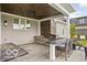 Covered outdoor kitchen features a built-in grill, stone accents, dark wood ceiling and bar-style seating at 12725 Parsons Gate, Carmel, IN 46032