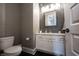 An updated powder room with a white vanity, decorative mirror, and wood-look wallpaper at 12725 Parsons Gate, Carmel, IN 46032