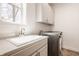 Bright laundry room features modern washer and dryer, sink, countertop, and ample storage cabinets at 16016 Viking Lair Rd, Westfield, IN 46074