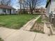 View of a spacious backyard with a long driveway, green grass, and some dandelions growing around at 1924 E Maryland St, Indianapolis, IN 46201