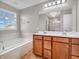 Well-lit bathroom featuring double sinks, a large mirror, soaking tub, and tiled shower at 1968 Saratoga Dr, Greenwood, IN 46143
