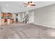 Open-concept living room with stairs and entry to kitchen, neutral walls, carpet, and a ceiling fan at 1968 Saratoga Dr, Greenwood, IN 46143