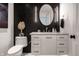 Stylish powder room featuring a modern vanity, decorative lighting, a round mirror, and black accent wall at 1995 W 116Th St, Carmel, IN 46032