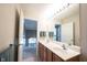 Bathroom featuring a double sink vanity with a large mirror reflecting a view of the house's hallway and staircase at 2261 Mustang Chase Dr, Carmel, IN 46074