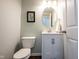 Powder room featuring a vanity with marble countertop, round mirror, and tiled floors at 2261 Mustang Chase Dr, Carmel, IN 46074