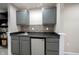 Basement kitchenette area with gray cabinets, granite counters, backsplash, sink, and mini-fridge at 2261 Mustang Chase Dr, Carmel, IN 46074