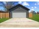Garage with a white garage door, concrete driveway, green grass, and a wooden fence at 2325 E Brookside Ave, Indianapolis, IN 46218