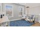 Bright sitting area with hardwood floors, blue rug, and two chairs next to a stairway at 2325 E Brookside Ave, Indianapolis, IN 46218