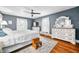 Bright bedroom featuring hardwood floors, white trim, gray walls, ceiling fan, and a large window at 3515 Guilford Ave, Indianapolis, IN 46205