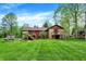 Expansive green lawn and trees surround a red two-story home with stone accents and wood decks at 3875 Arrowhead Ct, Greenfield, IN 46140