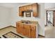 Basement kitchenette with wooden cabinets, double sink and an adjacent doorway to another room at 3875 Arrowhead Ct, Greenfield, IN 46140