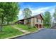 Unique stone house with an attached garage, brown roof, and a lush green lawn with wooden walkway at 3875 Arrowhead Ct, Greenfield, IN 46140
