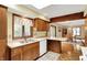 Functional kitchen with wood cabinets, bright lighting, a double sink, and connection to dining space at 3875 Arrowhead Ct, Greenfield, IN 46140