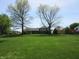 Large, grassy backyard showcasing the rear of the property with mature trees and landscaping at 4166 Cobblestone Way, Greenwood, IN 46143